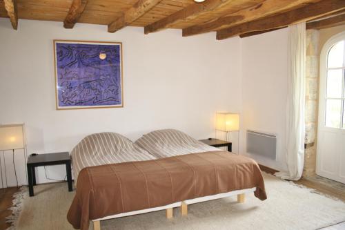 VillarsLa Verte Dordogne的卧室配有一张床,墙上挂有绘画作品