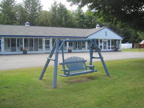 巴特利特北美殖民地汽车旅馆和小屋的坐在建筑物前面的草上的一个蓝色长椅