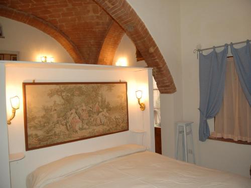 博恩孔文托Monolocale a Buonconvento的卧室,墙上挂着一幅画,位于床上方