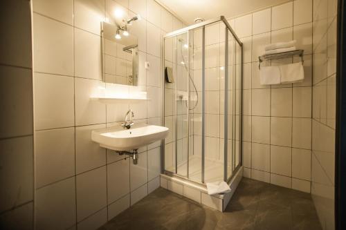 克伊克特鲁斯酒店的一间带玻璃淋浴和水槽的浴室