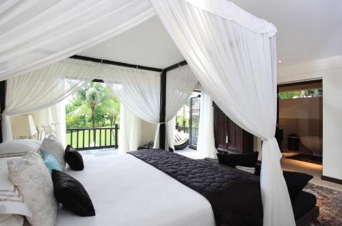 海神庙阿朱纳别墅酒店的卧室配有带窗帘的大型白色床