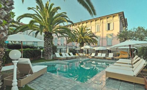利多迪卡马约雷欧洲大酒店 的一座带椅子和遮阳伞的游泳池位于一座建筑旁边