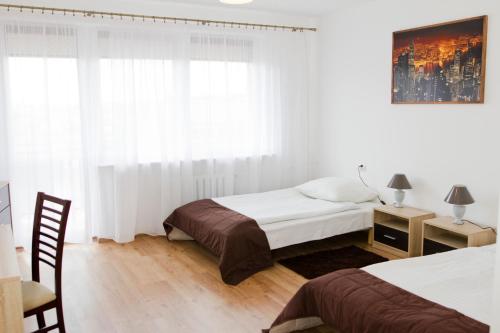 姆瓦瓦Hotel Mława的一间卧室设有两张床、一张桌子和一个窗口。