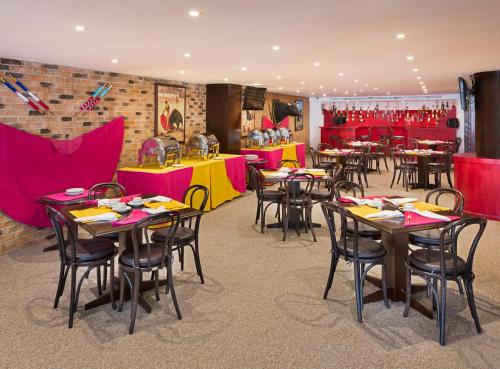 阿瓜斯卡连特斯弗朗西亚阿瓜斯卡连特斯酒店的一间设有桌椅的餐厅,餐厅红色和黄色