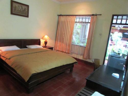 沙努尔格利亚阿玉酒店 的一间卧室配有一张床、一张书桌和一个窗户。