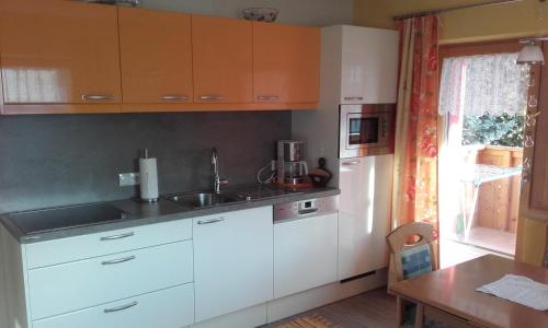 瑙德斯Haus Sagl的厨房配有白色橱柜、水槽和桌子