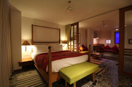 拉杰果德The Sky Imperial Aarivaa Luxury HomeStay的一间卧室设有一张大床和一个绿色长凳