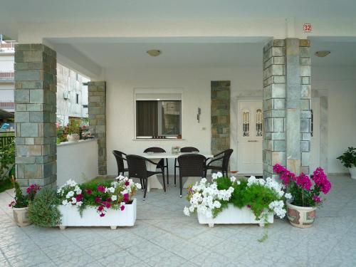 奥林匹亚基·阿克蒂Frideriki Apartments的一个带鲜花和桌椅的庭院