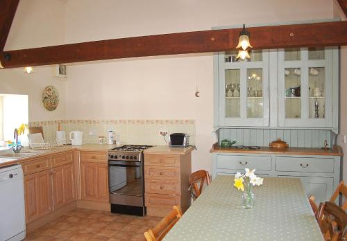 ColytonOld Orchard Cottage的厨房配有桌子和炉灶。 顶部烤箱
