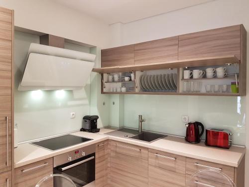 塞萨洛尼基Laura White Tower Apartment的厨房配有木制橱柜、水槽和炉灶。