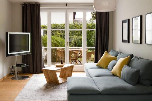 加尔米施-帕滕基兴Alpenhof Garnihotel & Ferienwohnungen的客厅配有蓝色的沙发和电视