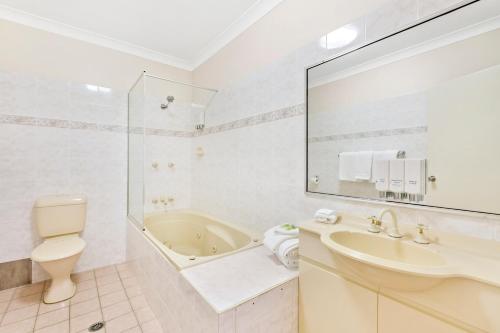 利斯莫尔舒适先得汽车旅馆 的带浴缸、盥洗盆和卫生间的浴室