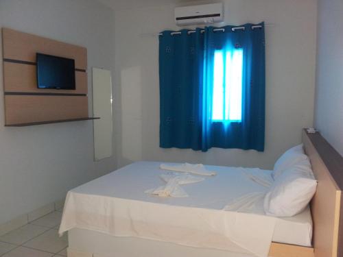 卡拉瓜塔图巴Hotel Cavalo Marinho Suítes的卧室配有白色床和蓝色窗帘