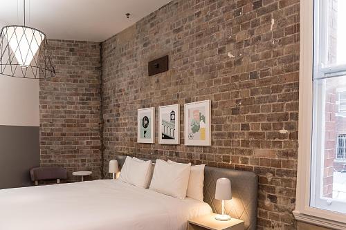 悉尼阿尔提莫酒店的一间卧室设有砖墙和一张床