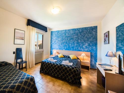 圣奇诺·迪·蒙塔尼亚中央酒店的一间卧室配有两张床、一张桌子和一台电视。