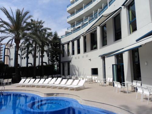 甘迪亚Hotel Principal afiliado a RH的一座带椅子的游泳池以及一座建筑