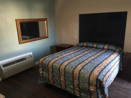 洛杉矶帕克汽车旅馆的一间卧室配有一张床、镜子和风扇
