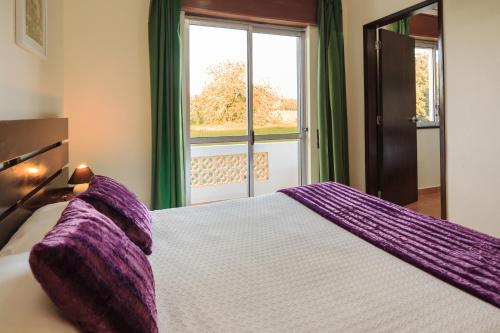 博利凯梅奥利维拉旅馆的一间卧室配有一张带紫色床单的大床和窗户。