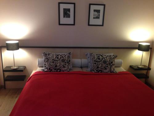 久洛Albatrosz Apartman的一间卧室配有一张红色的床和两盏灯