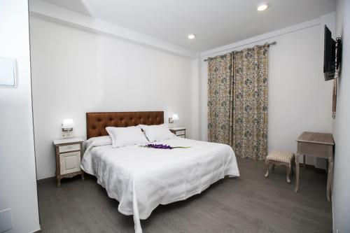 内尔哈巴哈马尔精品旅馆的白色卧室配有一张大床和一张书桌