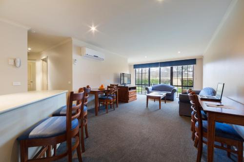 堪培拉Canberra Parklands Central Apartment Hotel Official的一间带酒吧的客厅和一间餐厅