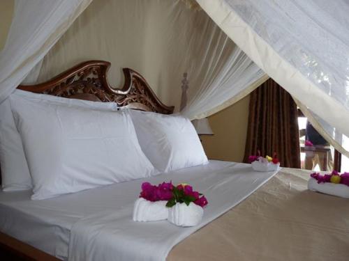 WeshaPemba Misali Sunset Beach的一张带两个白色枕头的床,床上有鲜花
