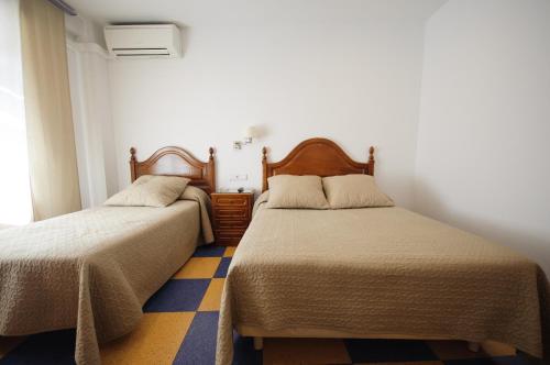 贝纳文特特露查餐厅旅馆的一间卧室设有两张床,铺有黄色和蓝色的地板。