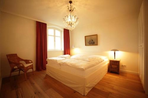 霍恩宁多夫Appartement Schloß - Hohen Niendorf的卧室配有一张白色大床和吊灯。