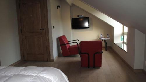 鲁汶Hotel Guesthouse Begijnhof的一间卧室配有两张红色椅子和电视