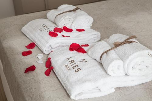 卡萨拉诺B&B Aries的床上的一组毛巾,上面有红色玫瑰花垫