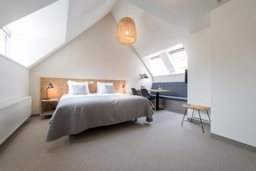 东弗利兰Leut logies & Boutiquehotel het Eiland的白色卧室配有床和书桌