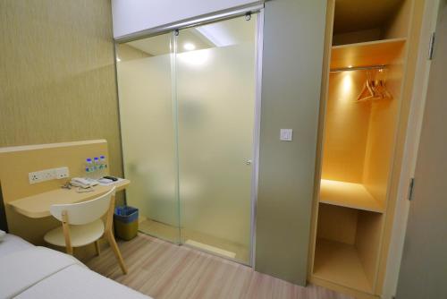 八打灵再也33 Boutique Hotel Bandar Sunway的配有一张床和一张书桌的玻璃淋浴间