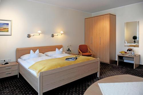 利普施塔特Hotel-Pension Pöhling的配有一张床和一把椅子的酒店客房