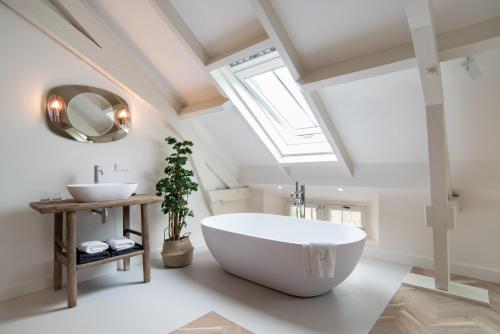 阿布考德Boutique Hotel De Witte Dame的浴室配有大型白色浴缸和水槽