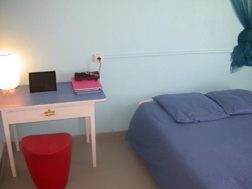 圣安娜Maison de Vacances à St Anne Martinique的一间卧室配有一张桌子、一张床和一张桌子及一台笔记本电脑