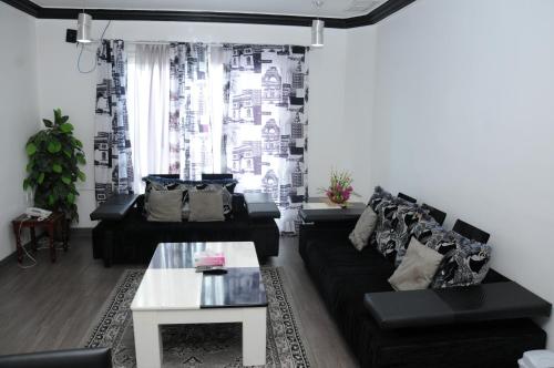 科威特奥林扎塔楼品质公寓的客厅配有黑色沙发和桌子