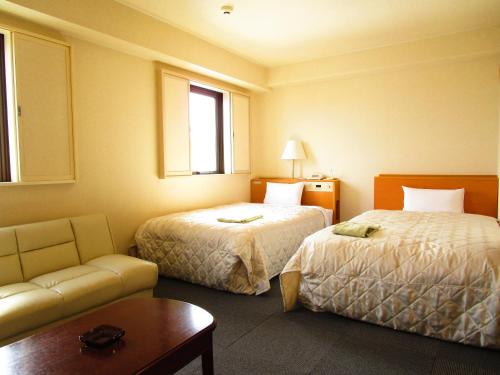 大仙市大曲绿色酒店的酒店客房,设有两张床和一张沙发