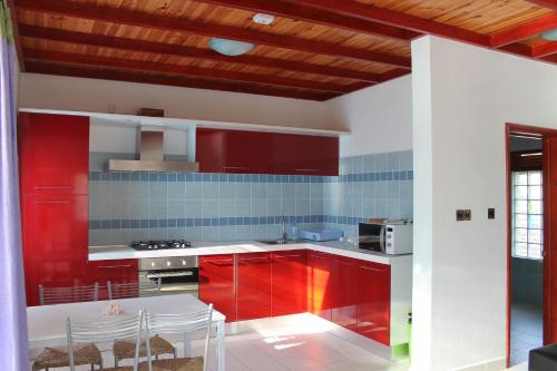 马埃岛贝拉扎尔区绿蓝海滩公寓的厨房配有红色橱柜和桌椅