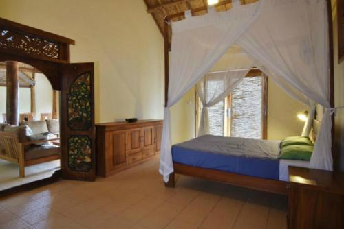 Bumbang布鲁斯海德奥特旅馆的一间卧室配有一张天蓬床和一把椅子