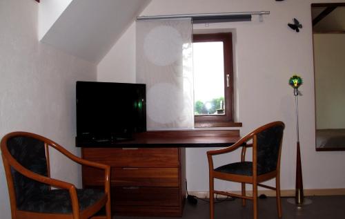 Esneux石站公寓式酒店的客房设有一张桌子、一台电视和两把椅子
