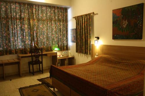 博帕尔Ivy Suites的一间卧室配有一张床、一张书桌和一个窗户。