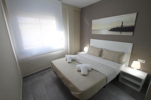 坎布里尔斯Apartamentos Cambrils Playa Spa的一间卧室配有一张床,上面有两条毛巾