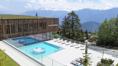 安塞热Holidays Groupes Anzère的一个带椅子的游泳池,背景是山脉