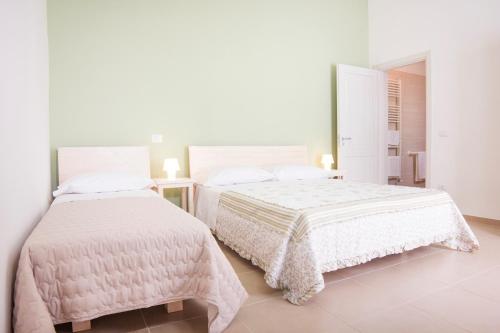 GuagnanoNonna Nina的一间白色卧室,配有两张床和镜子