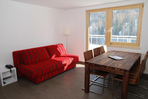萨姆瑙恩Chasa Sulai Appartements的客厅配有红色的沙发和木桌