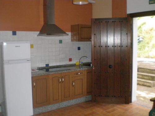 CarcabueyApartamentos Rurales El Cañuelo de Carcabuey的厨房配有木制橱柜和白色冰箱。