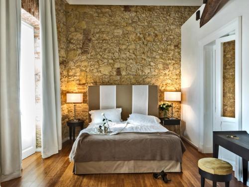 卡利亚里芬妮别墅酒店的一间卧室设有一张床和石墙