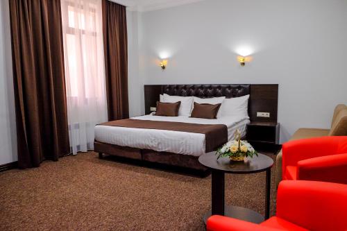 阿克套ZhanaOtel Hotel的酒店客房,配有一张床和一张红色椅子