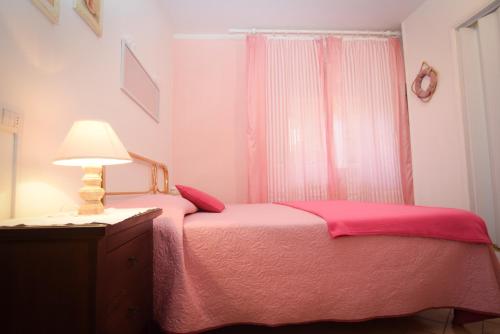 圣温琴佐丹尼亚别墅酒店的卧室配有粉红色的床和灯