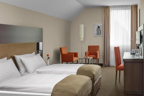 达姆施塔特IntercityHotel Darmstadt的酒店客房,配有两张床和椅子
